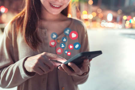 Hands of woman using a social media marketing concept on mobile smartphone in the street with icon social media and social network.の写真素材