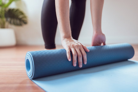 Woman roll out yoga mat for preparation, Female work out by exercise yoga in living room at home.の写真素材