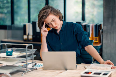 Young beautiful serious woman working with laptop while sitting at table in office.の写真素材