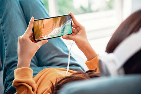 Online movie stream with smartphone. Woman watching film on mobile phone with imaginary video player service.の写真素材