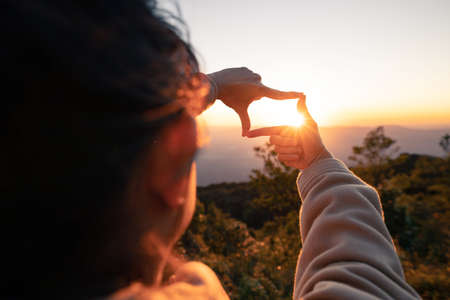 New year planning and vision concept, Close up of woman hands making frame gesture with sunset,...