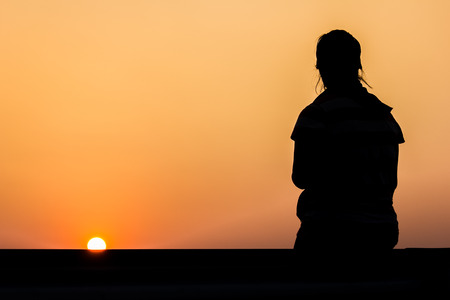 young woman silhouette at sunsetの写真素材