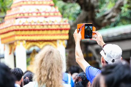 Man taking pictures of the architecture of Thailand with a smartphone.の写真素材