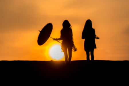 Blurred silhouette of Young woman relaxing in summer sunset sky outdoor. People freedom style.の写真素材