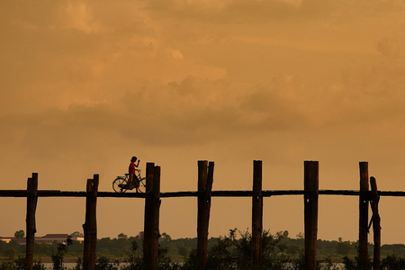 Silhouetted person with a bike on U Bein Bridge at sunset, Amarapura, Mandalay region, Myanmarの写真素材