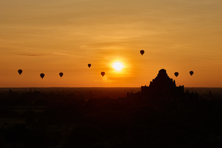 Scenic sunrise with many hot air balloons above Bagan in Myanmar. Bagan is an ancient city with...