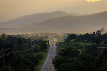 rural road in green grass and orange sunsetの写真素材