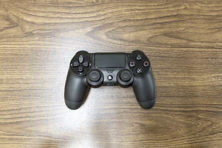 Bangkok,Thailand, -17 May 2016 : The new Sony Dualshock 4 with PlayStation 4 on Wood front view....