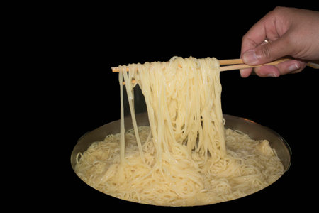 a hand holds chopstick lifting up noodlesの写真素材