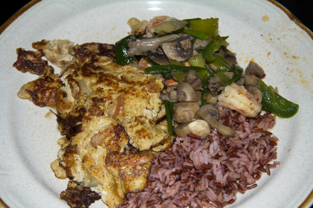 a dish of brown rice with fried eggs and stir fryの写真素材