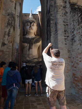 a tourist taking photo a big buddha statue Sukhothai Historic Parkのeditorial素材