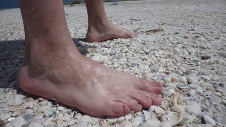 man feet stand on shells on the beachの写真素材