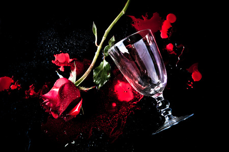 dramatic a red rose with wine glass on bloodの写真素材