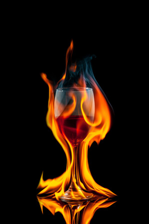 glass of wine on black background with fire splashの写真素材