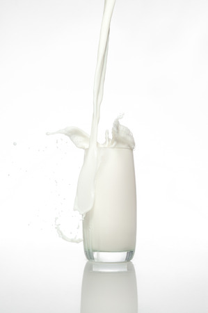 pouring a glass of milk creating splashの写真素材