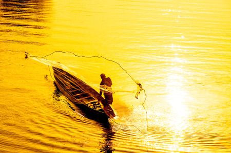 throwing fishing net during sunset ,Thailandの写真素材
