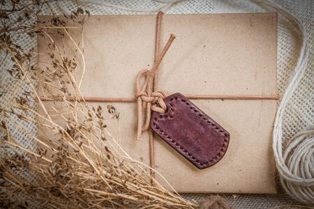 Gift boxes with labels made of leather with rope on gunny sack vintage style backgroundの写真素材