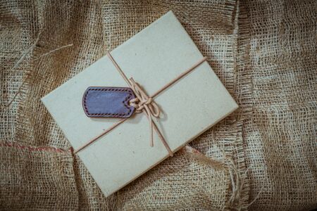Gift boxes with labels made of leather with rope on gunny sack vintage style backgroundの写真素材