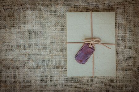 Gift boxes with labels made of leather with rope on gunny sack vintage style background
