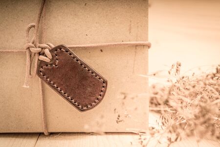 Gift boxes with labels made of leather with rope on gunny sack vintage style backgroundの写真素材
