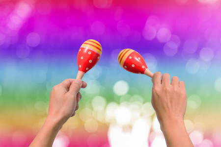 Hand holds maracas on abstract blurry bokeh backgroundの写真素材