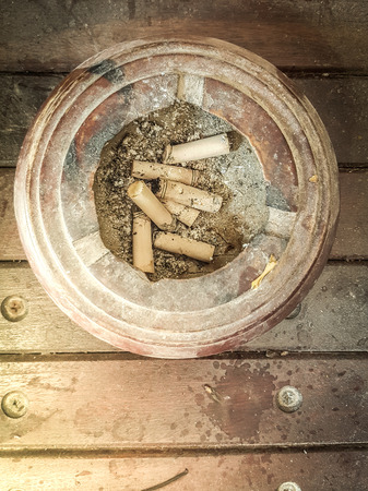 Old cigarette butts left in ashtrays made of wood.の写真素材