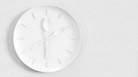 Cutlery on a white dish that resembles a clock. Place on an uneven cloth and copy space for your text. Minimal idea concept, 3D Render.の写真素材