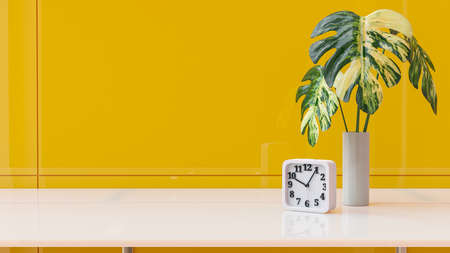 White square clock on desk with beautiful tree. in yellow office. Yellow baceground and copy space for your text. Business idea concept, 3D Render.の写真素材