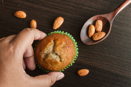 Hand holding banana cup cake on wooden background. Dessert Thai style.の写真素材