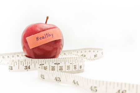 Measuring tape wrapped around a red apple as a symbol of diet.の写真素材