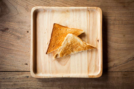 Two toast sliced on wooden plate. Top view.