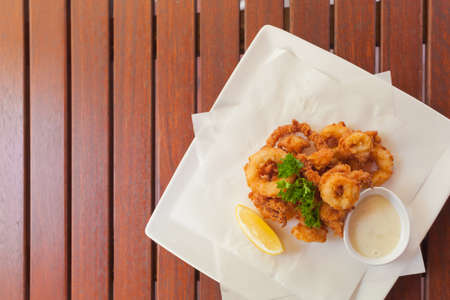 Delicious golden crispy squid ring on plate with sauceの写真素材