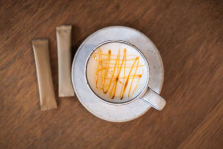 Top view of caramel latte in cup on wooden table.の写真素材