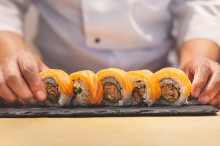 Hands chef preparing japanese sushi, salmon roll.の写真素材