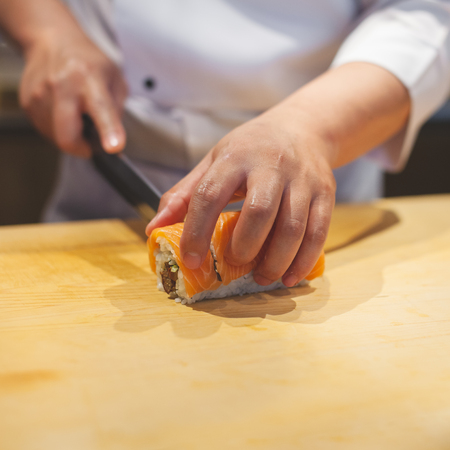 Chef sliced salmon roll. Hands preparing japanese sushi.の写真素材