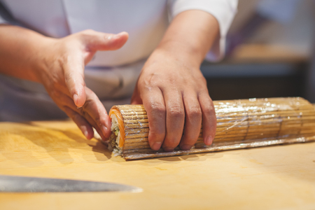 Cook hands making japanese sushi roll. Japanese chef preparing sushi roll with rice on nori leaf.の写真素材