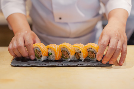 Hands chef preparing japanese sushi, salmon roll.の写真素材