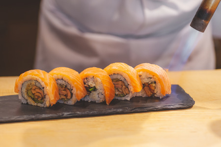 Hands chef preparing japanese sushi, Burn fire on salmon roll.の写真素材