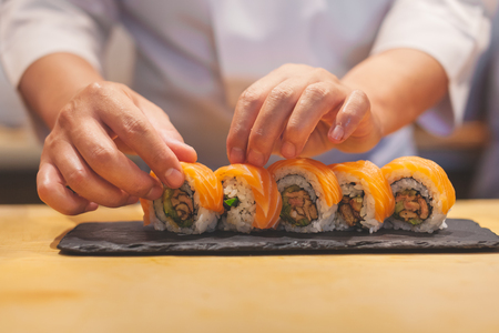Hands chef preparing japanese sushi, salmon roll.の写真素材