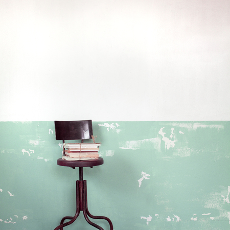 Old books on brown chairs, on white and green vintage wall.の写真素材