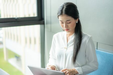 Concentrated young women working on laptop while sitting at working place. Hard work ensures success.の写真素材