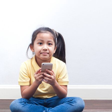 Asian Kid girl playing smart phone. Children technology and communication concept.の写真素材