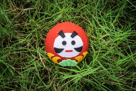 Hold daruma doll on the background of blurred tree and sunshine in dayligth using wallpaper or background.の写真素材