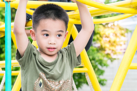 The asian boy is playing  a playground  on blurred tree backgroud village of funny.