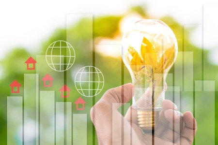 Men hold light bulbs with sun in the daytime, with bokeh backdrops and home in cloud  using wallpaper or background for idea work for business work.の写真素材