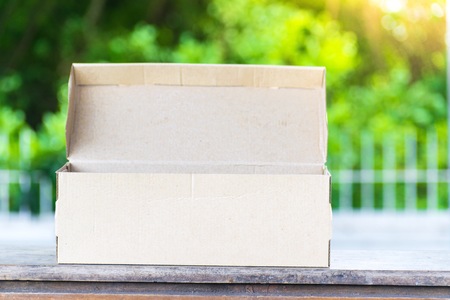 Carton on the wood and tree blurry bokeh background in garden. Using wallpaper for package work...