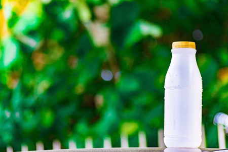 plastic bottle white on the wood and tree blurry bokeh background in garden. Using wallpaper for package work photo.の写真素材