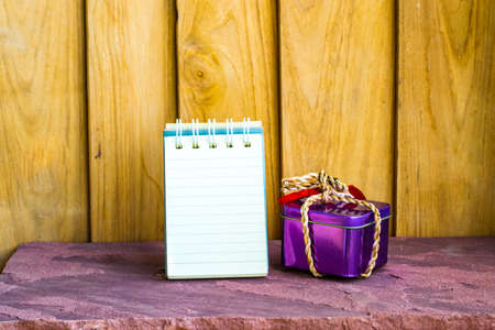 Notepad with  gift Box a wood background. Using wallpaper or background. For package or product and  note copy space.の写真素材
