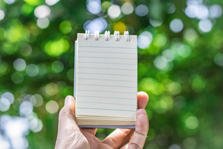 Notepad with pencil on tree blurry background in garden . using wallpaper or background for...