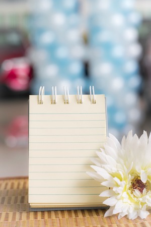 Notepad with wine glass on wood board background.  Blurry in showroom car background. using wallpaper or background for education, business photo. Take note of the product for book with paper and concept or copy space.の写真素材